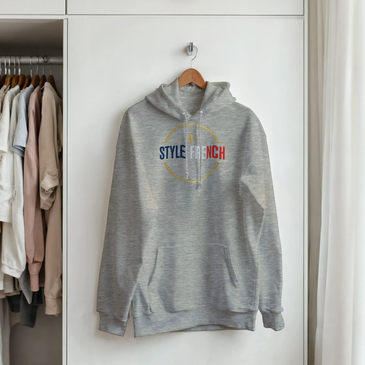 sweatshirt à capuche qualité supérieure France accroché à un portant dans une chambre tendance.