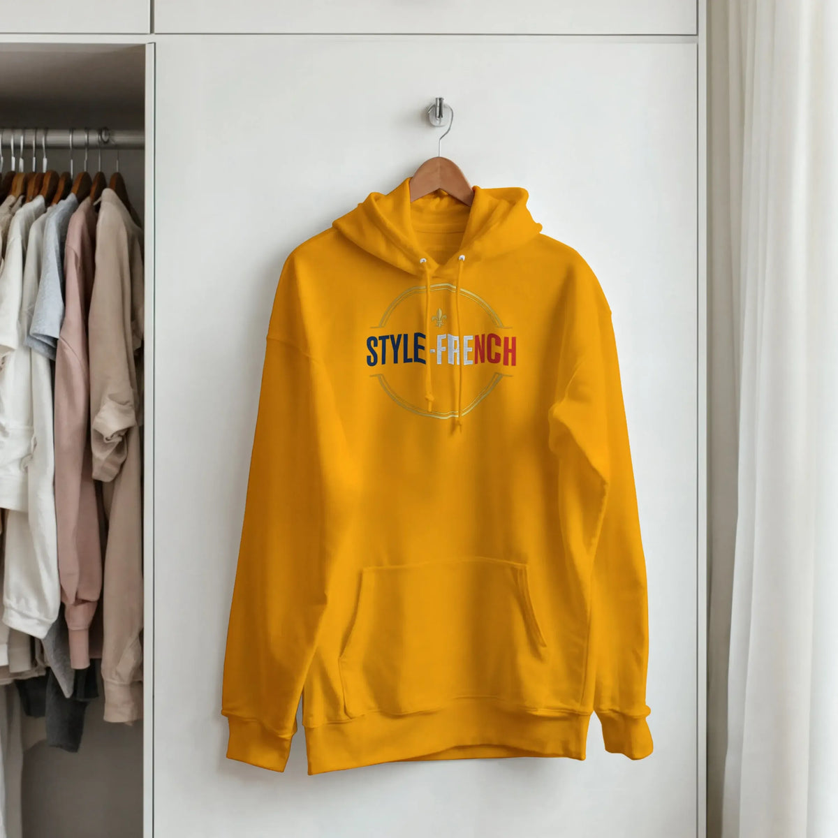 Sweatshirt à capuche qualité supérieure France en jaune, accroché dans une armoire.